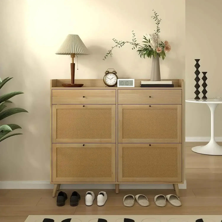 Rattan shoe cabinet displayed in a stylish interior with a lamp, clock, and decorative plants.