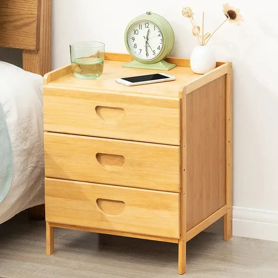 Wooden nightstand with clock, glass, and tablet on top in a bedroom setting