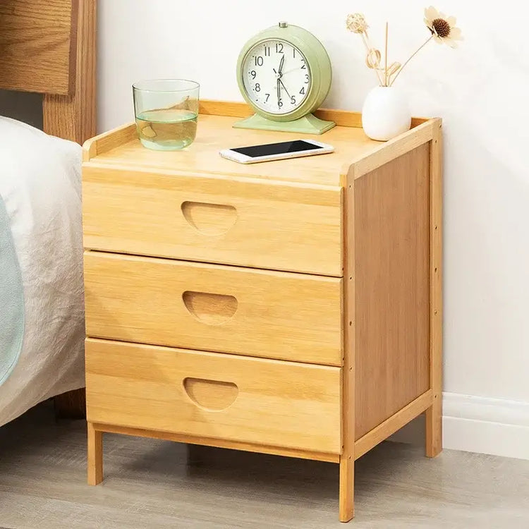 Wooden nightstand with clock, glass, and tablet on top in a bedroom setting
