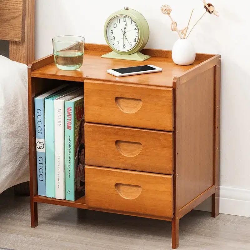 Wooden nightstand with books, a clock, and a glass on top next to a bed.