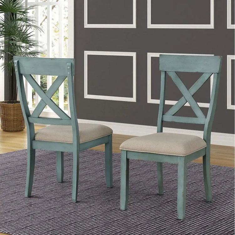 Two teal chairs with beige cushions on a gray rug in a room with framed pictures on the wall.