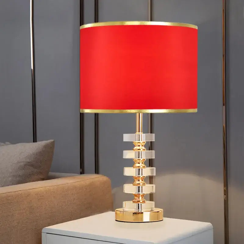 Modern crystal table lamp with fabric shade featuring a red shade and gold detailing, ideal for bedrooms and living rooms.