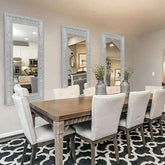 Large silver rhinestone mirror reflecting a dining area with elegant decor and comfortable seating.