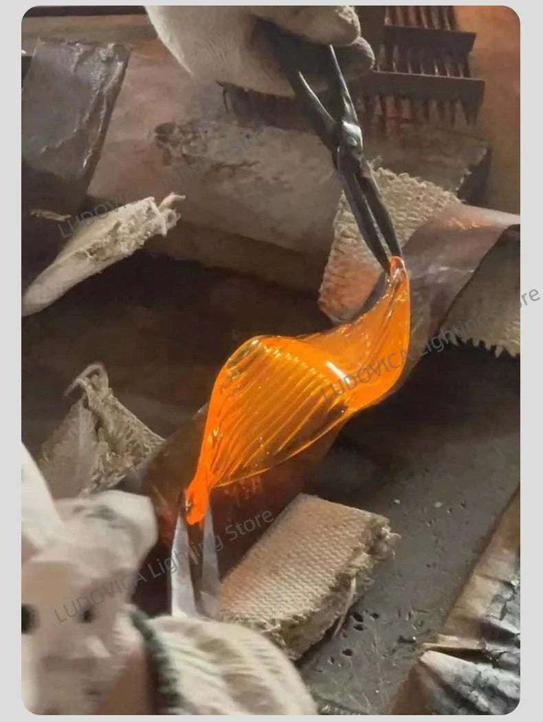 Person wearing gloves holding a tool with an orange handle over a metal surface