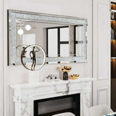 Large silver frameless wall mirror with sparkling crystal rhinestone border above white marble fireplace mantel
