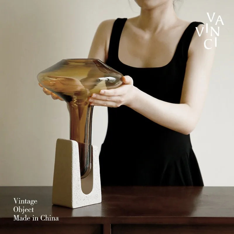 Person holding a vintage luxury glass vase with a unique design on a wooden table.