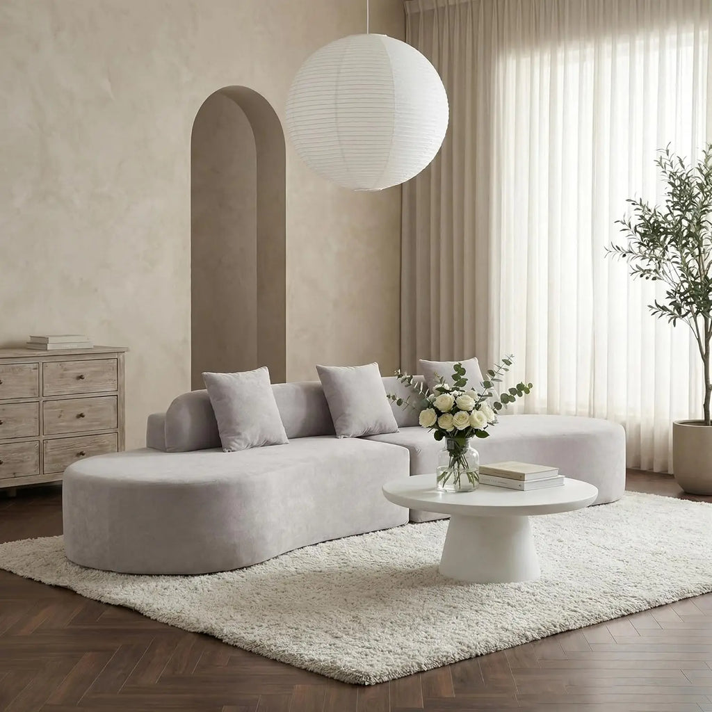 Modern living room with a gray sectional sofa, white coffee table, and decorative elements.