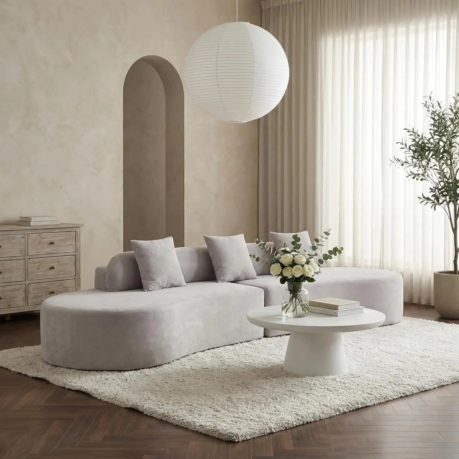 Modern living room with a gray sectional sofa, white coffee table, and decorative elements.