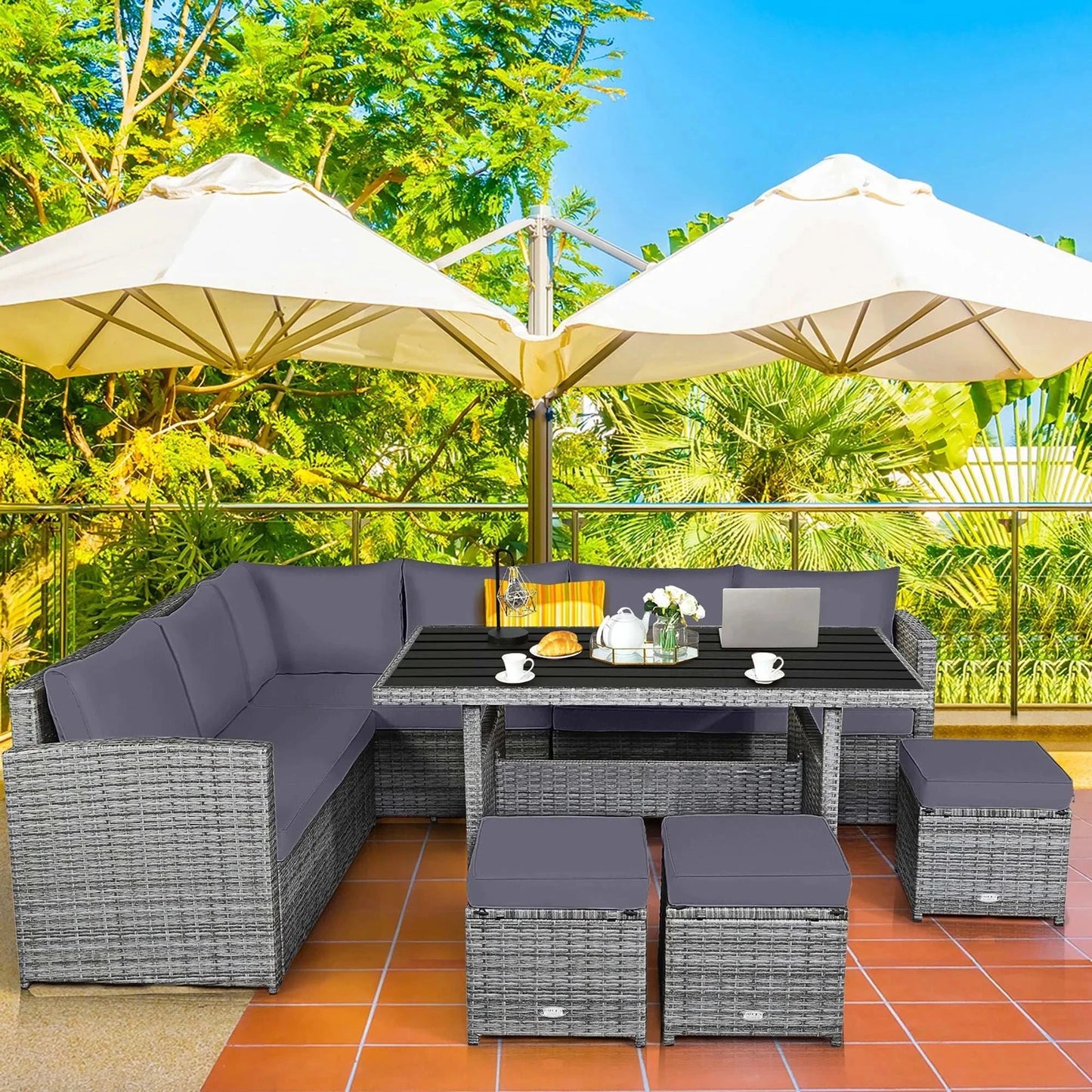 7 PCS Patio Rattan Dining Set with gray cushions, sectional sofa, table, ottomans, and large white patio umbrellas on outdoor terrace