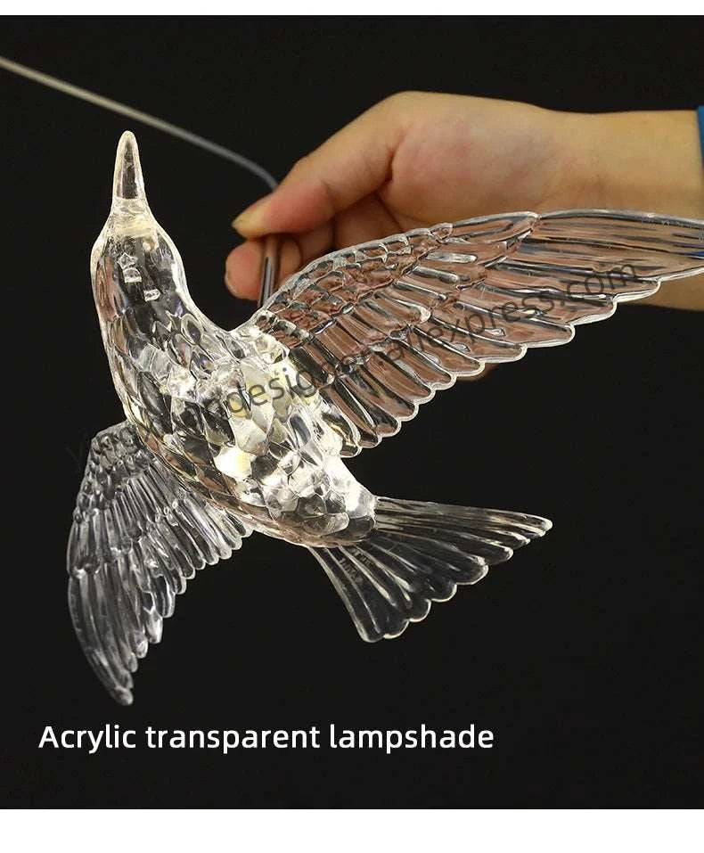 Acrylic transparent bird-shaped lampshade held by a hand against a black background