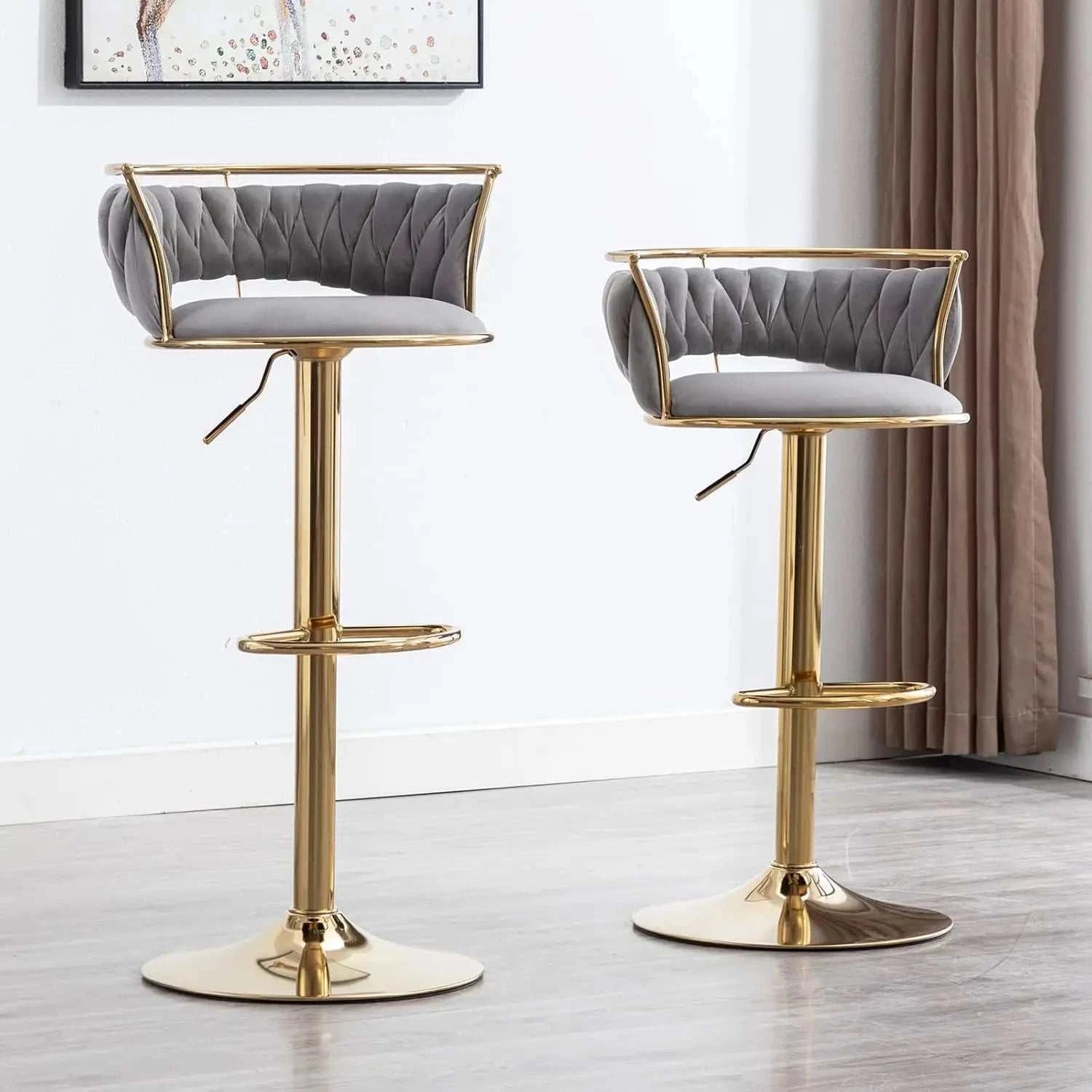 Two gray cushioned bar stools with gold metal legs in a room setting.