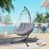 Hanging chair with gray cushion on a wooden deck with palm trees and ocean view