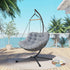 Hanging chair with gray cushion on a wooden deck with palm trees and ocean view