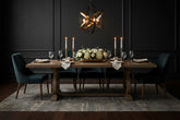 Elegantly decorated dining room with a chandelier a dark background and sphere light fixture and dark colored chairs 