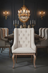 Beige upholstered chair with wooden legs, front-facing to show details Ina ding room setting with wall sconces, candelabras and chandelier