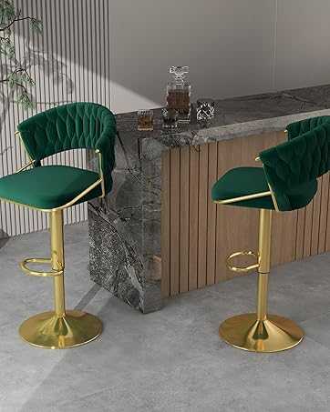 Two green velvet bar stools with gold legs in front of a marble countertop.